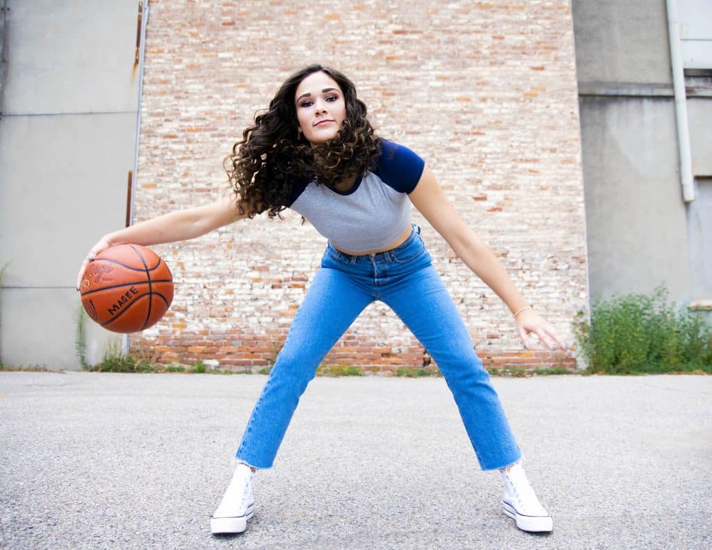 An action shot of a girl dribbling a basketball in front of a whitewashed brick wall in downtown Cincinnati.