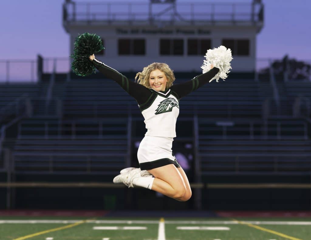 An image of a Bishop Brossart cheerleader in the air with her pom poms in Alexandria, Kentucky.