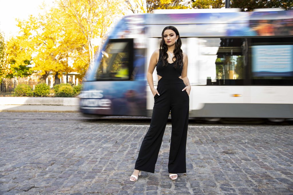 A dynamic portrait of a high school senior posed by Tonya Bolton Photography in front of a passing Cincinnati Streetcar with a blurred motion.