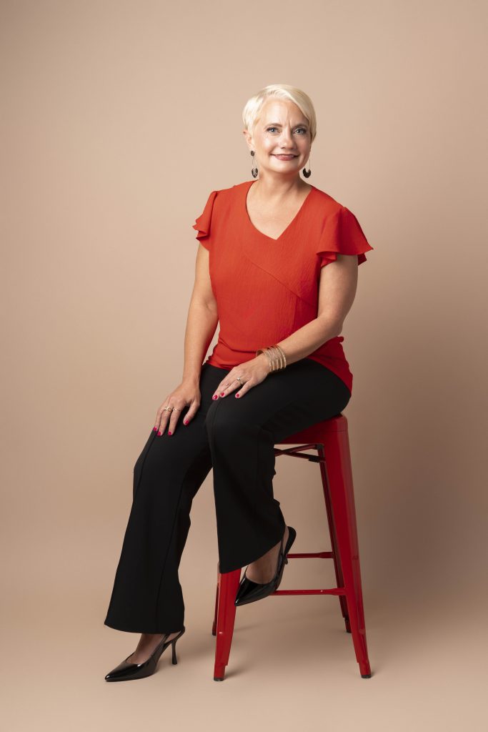 A business portrait of a woman on a neutral backdrop sitting on a stool by tonya bolton photography based in cincinnati.