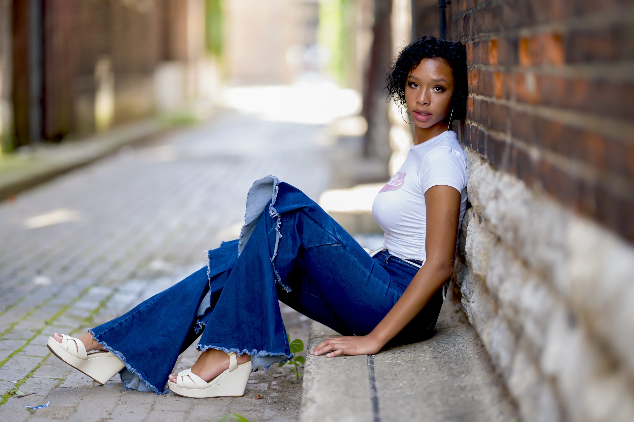 High school senior posing on a brick wall in a Cincinnati alley with tonya bolton photography.