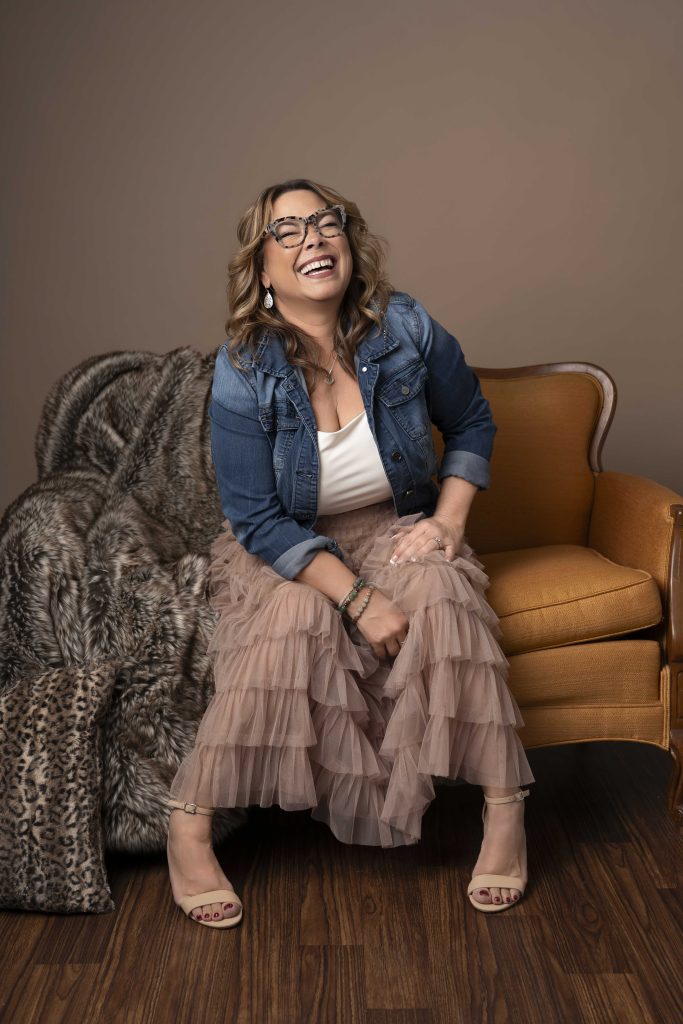 A candid portrait of a woman laughing while being photographed.