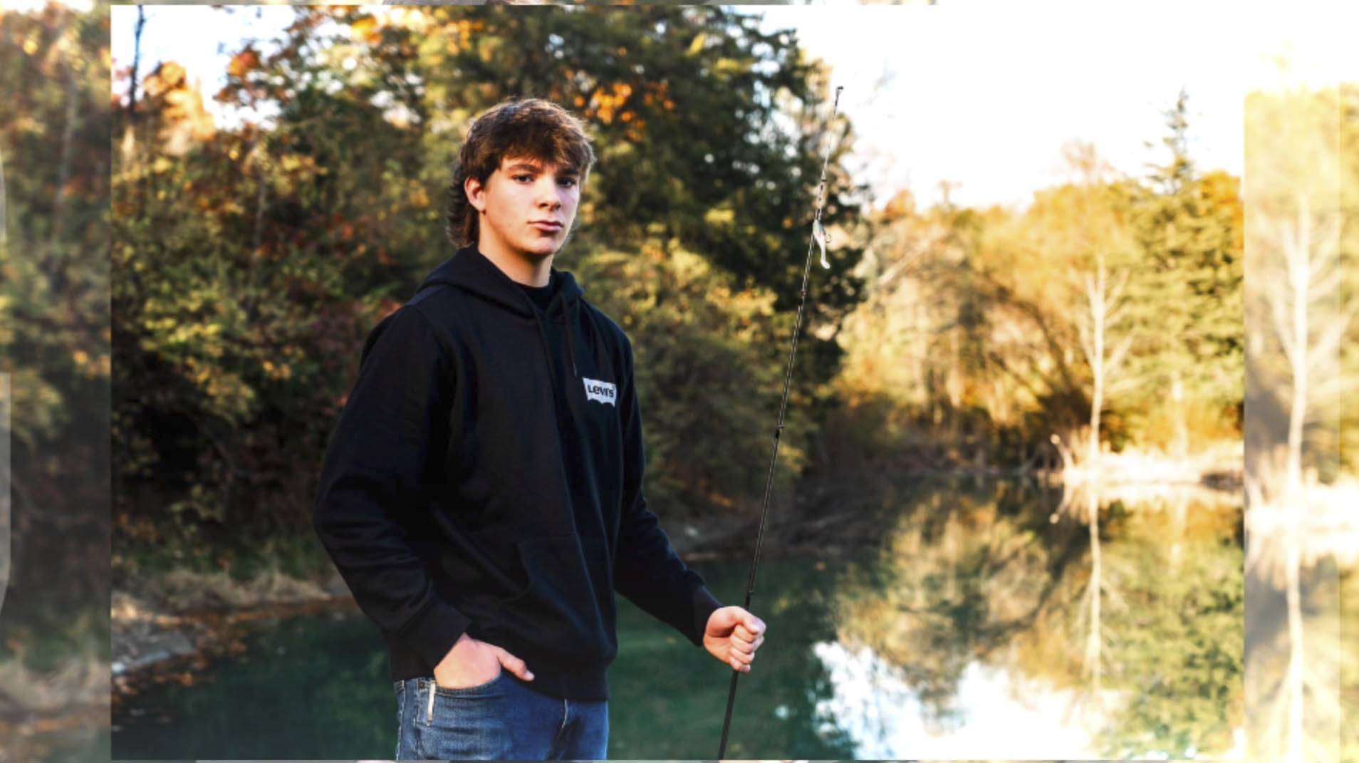 high school senior portrait of a boy fishing at a pond