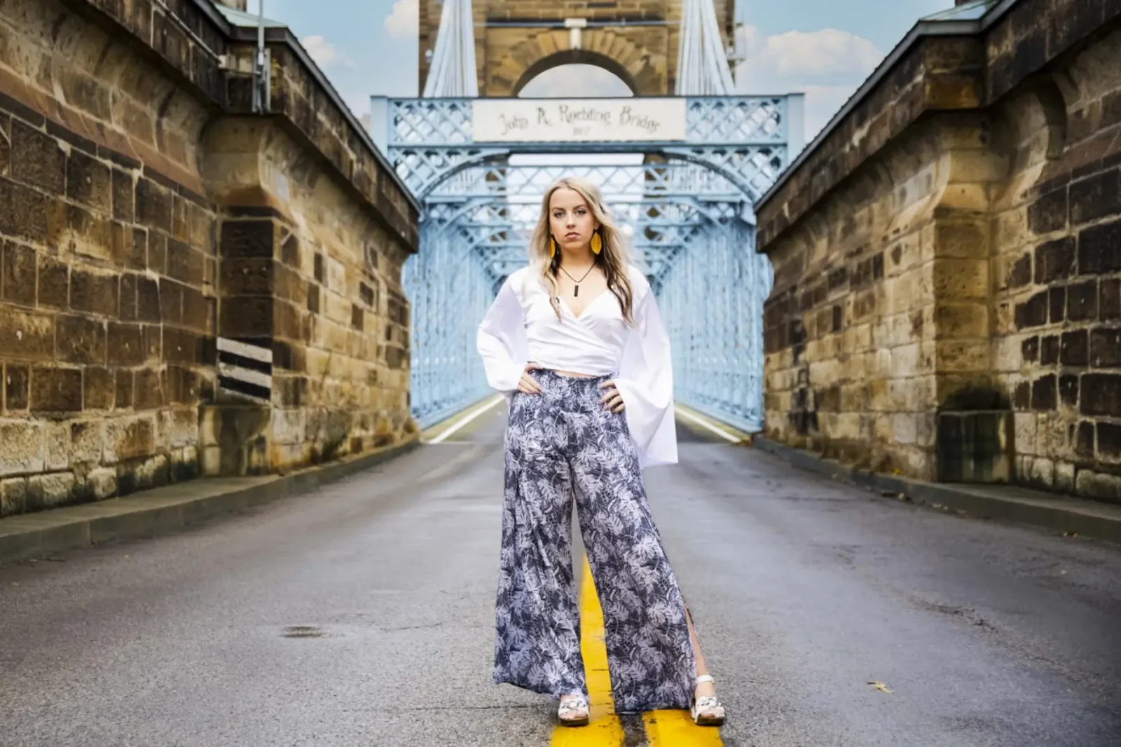 high school senior standing at the entrance of the roebling bridge in cincinnati ohio